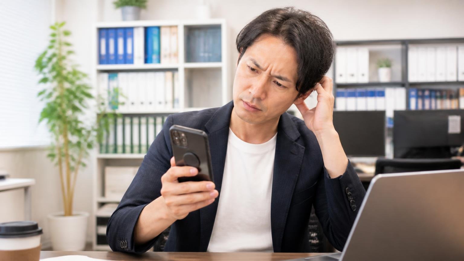 ユーザー投稿サイトでの評価は5点満点中4.6点 事務所でスマホの口コミ画面を見ながら首をかしげる男性1人
