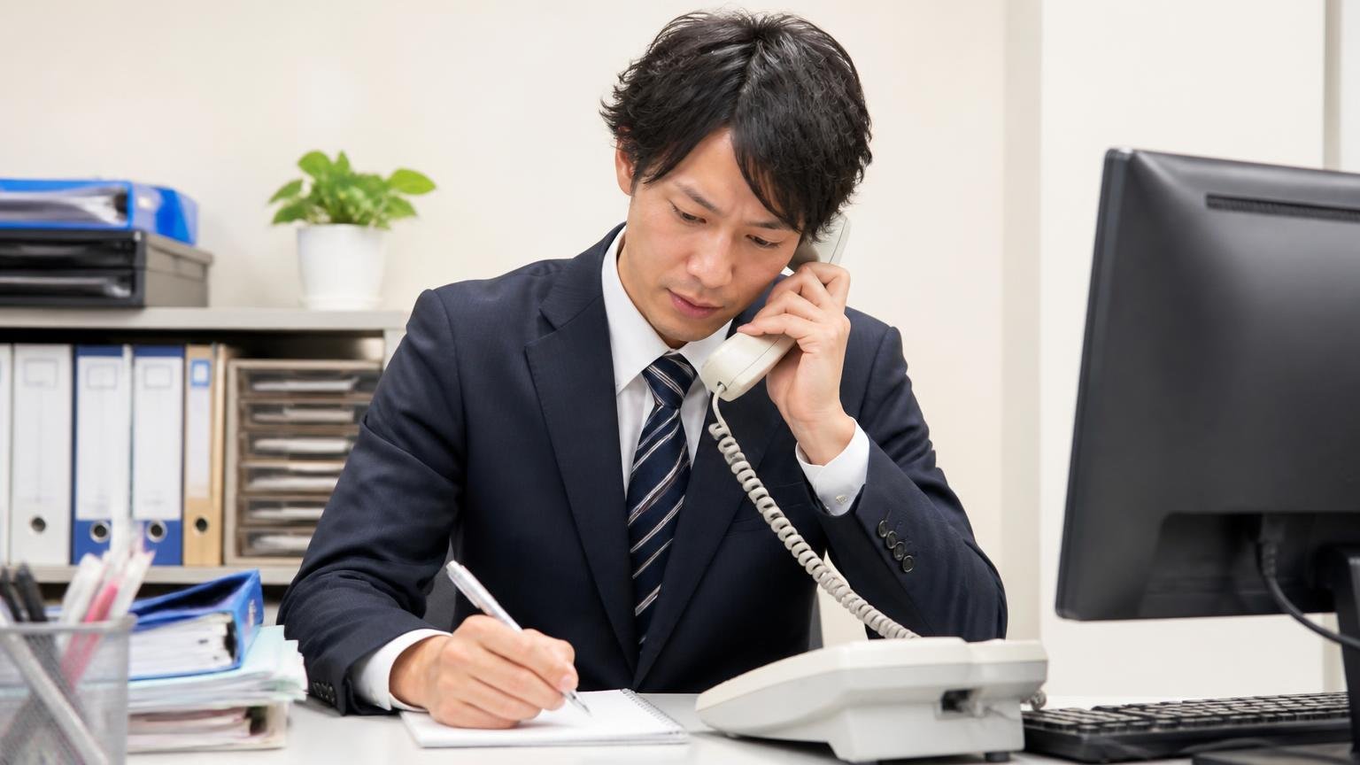 STEP1 送信元に直接、配信停止を依頼する。事務所の電話機の前で男性1人が受話器を持ちメモを取る