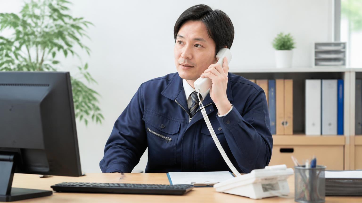 最後にもう一度、無料の出張査定と書類代行に対応している買取業者を確認しておく。事務所で男性1人が電話を手に取る