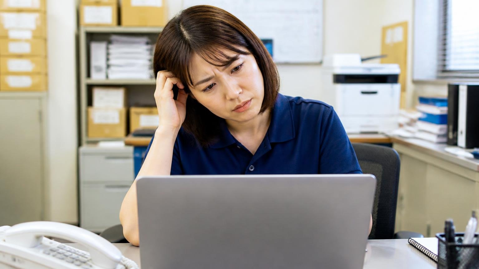 口コミサイトを調べた結果、運送会社の事務所でノートパソコンの検索画面を見つめる事務担当の女性1人が首をかしげる