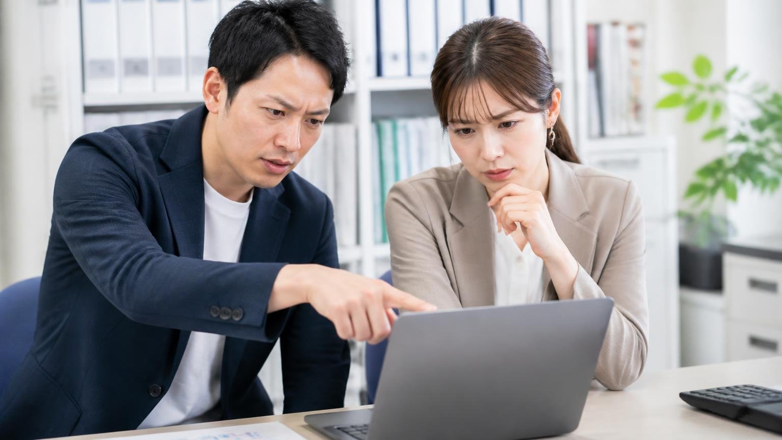 公式サイトに書いてあること、書いていないこと 事務所でパソコン画面を指さして話す男女2人、真剣な表情