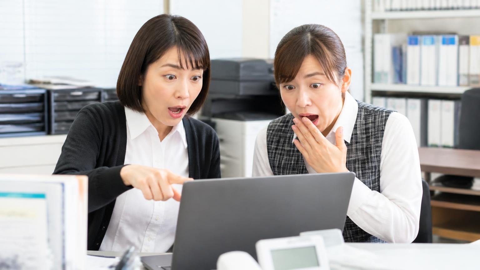 和歌山まで来てくれるか確かめる|営業所の事務所でパソコンの業者サイトを確認する2人の事務員が画面を指さして驚く場面