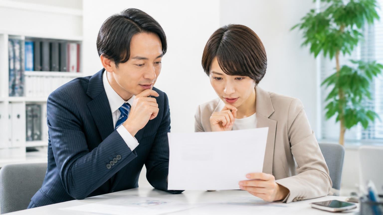 設立1977年・伊藤忠エネクス100%子会社の意味。事務所で会社概要を印刷した紙を見る男女2人
