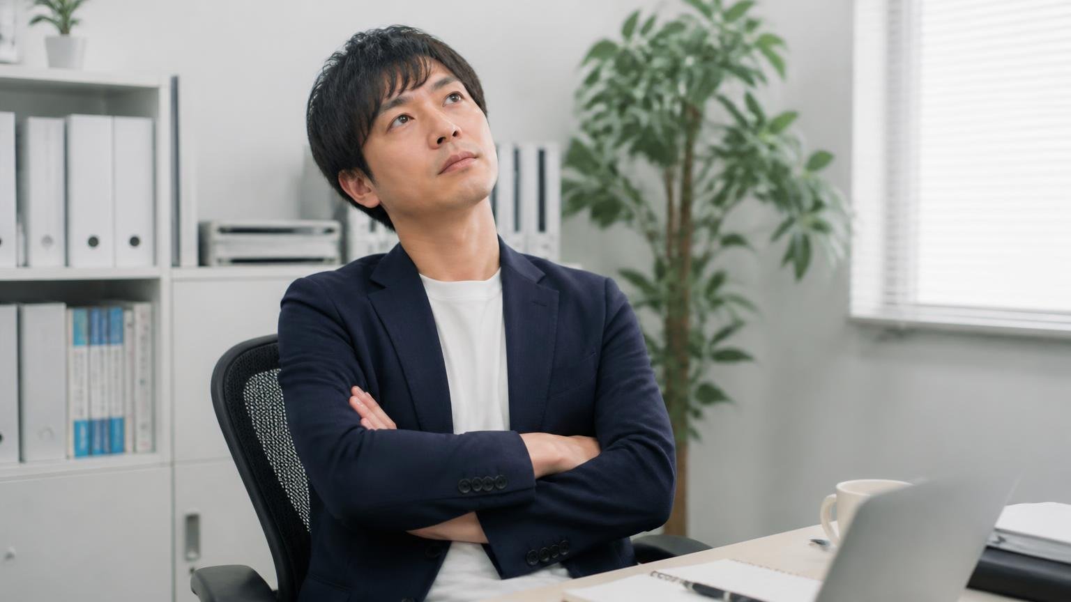 問題が起きていない可能性を考える場面。事務所の椅子で腕を組み天井を見上げて考え込む男性1人