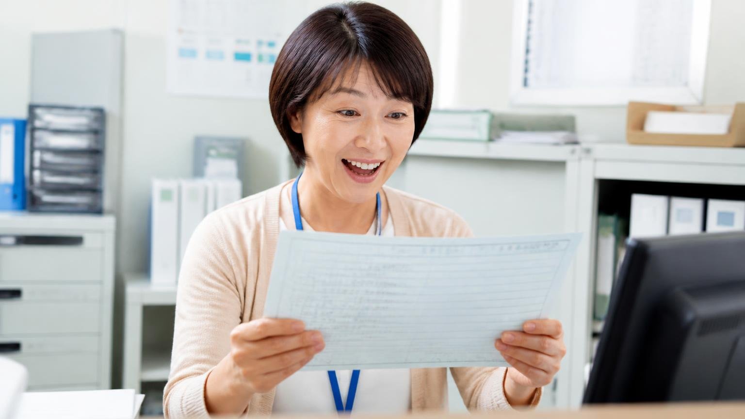 名義変更は15日以内が法律のルール、完了の連絡を約束してもらう 事務所で届いたトラックの車検証の写しを確認してほっとする女性事務員