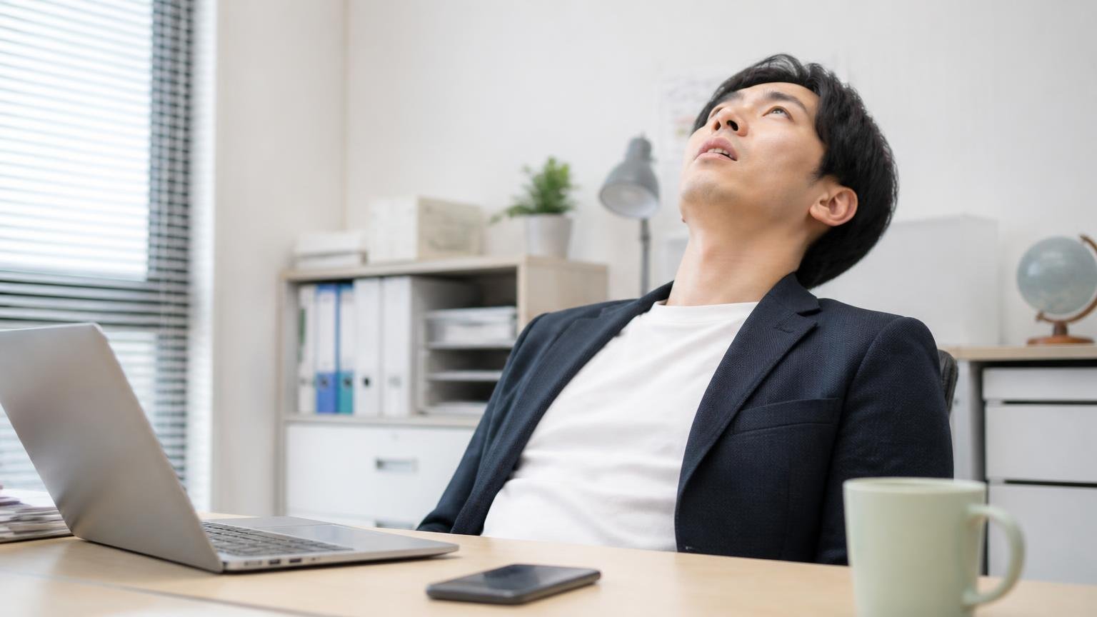 買取金額に触れた口コミが15件のうち1件もない。事務所でスマホを置いて天井を仰ぐ男性1人が脱力した表情