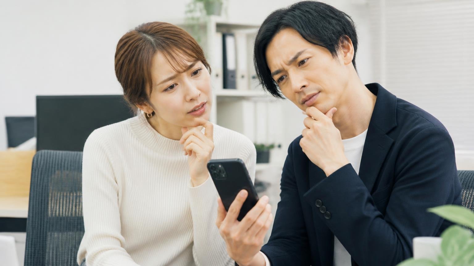 Googleマップの★は「件数」と「誰が何について書いたか」で読む 事務所でスマホの口コミ画面を見せ合う男女2人が首をかしげる