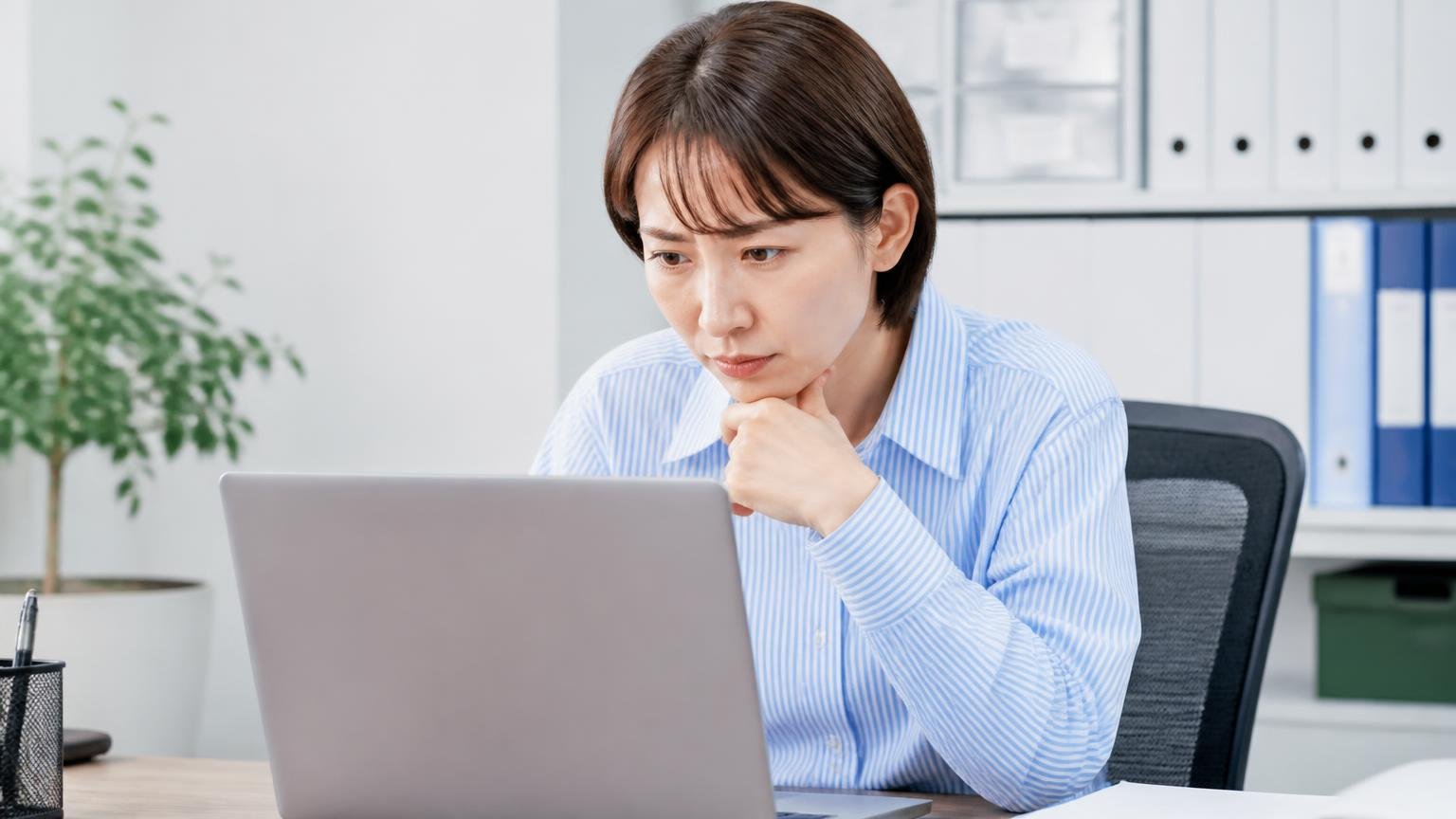 物差し①会社の実体:所在地・連絡先・営業時間が公式で確認できるか 事務所でパソコンの会社概要ページを確認する場面 事務担当1人 真剣に画面を見つめる